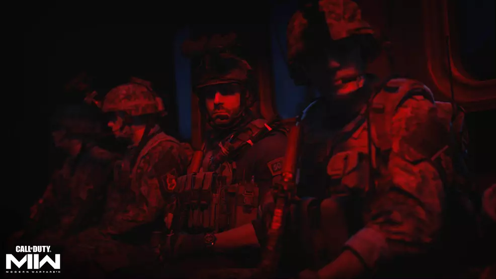 Image shows four soldiers lit with red light in the back of a vehicle