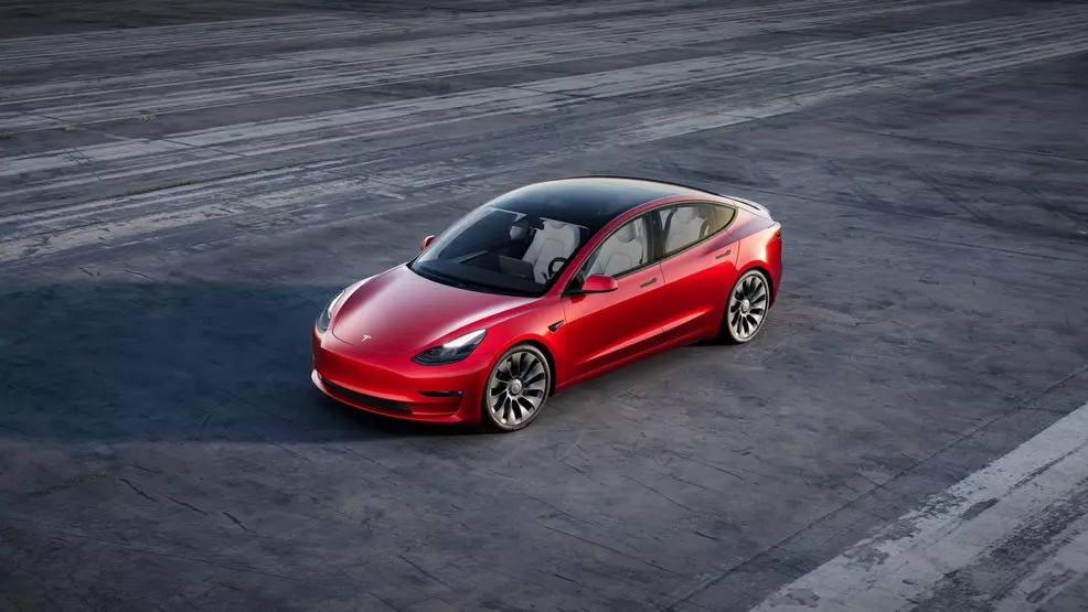 An aerial shot of a red Model 3 with a black roof.