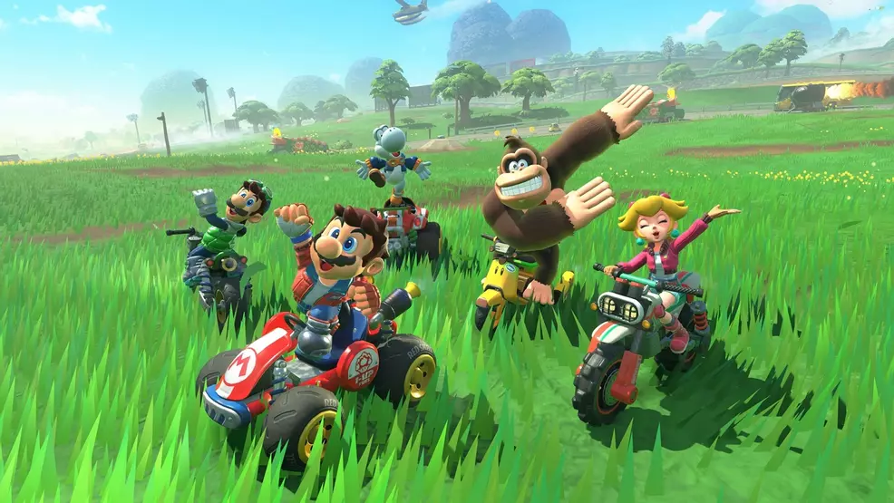 Mario, peach, Luigi, Donkey Kong, and Yoshi riding karts through a field.